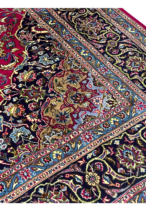 Close-up of Persian Mashad rug border showing navy floral pattern with light blue guard border and red field details.