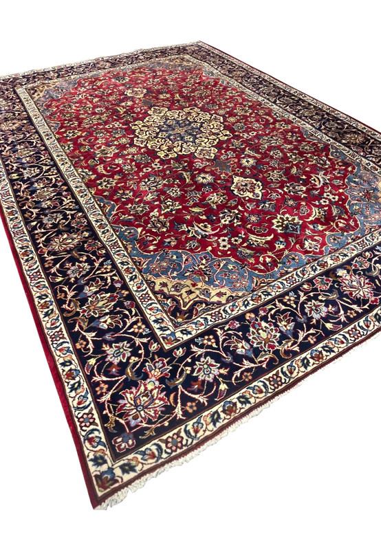 Angled view of 8'5 x 11'8 Persian Isfahan rug highlighting medallion, red field, and navy border.