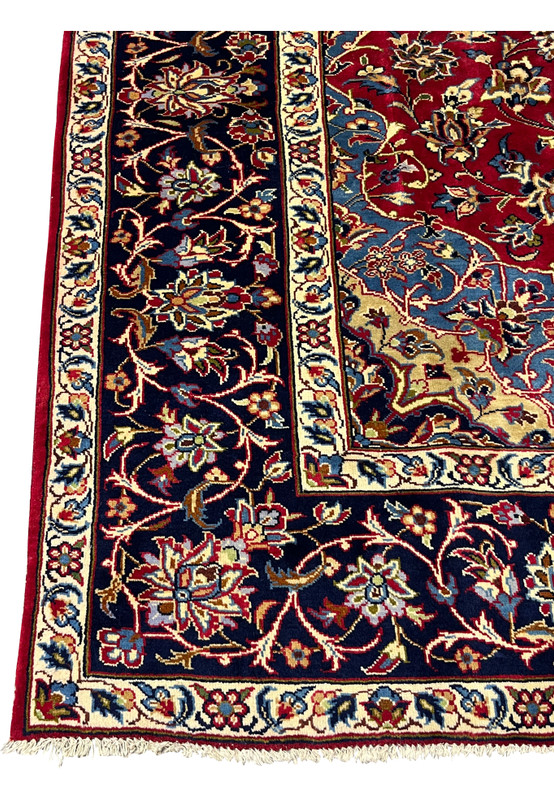 Corner detail of 8'5 x 11'8 Persian Isfahan rug showing blue corner, ivory edge, and floral border.