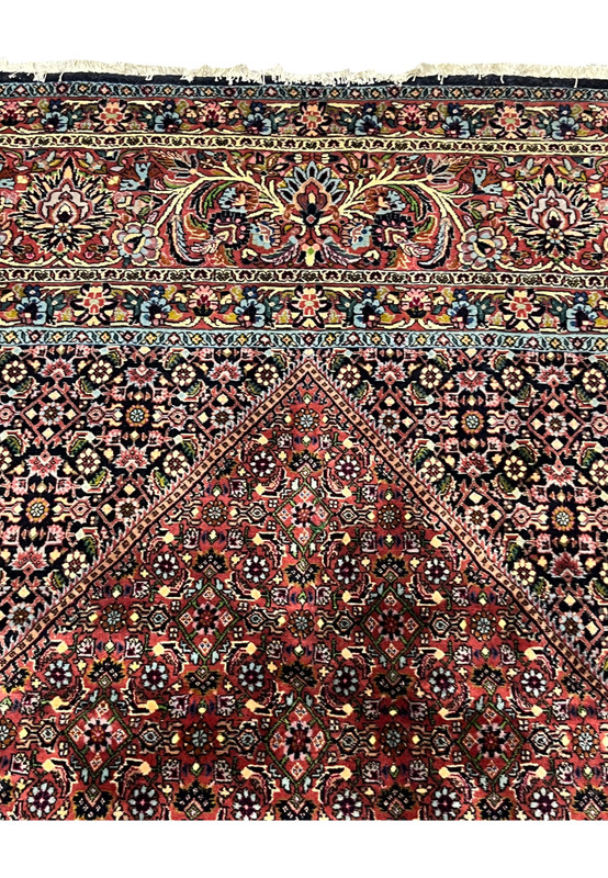 Upper field of Persian Bijar rug with ivory floral spandrels and multilayer geometric medallion.