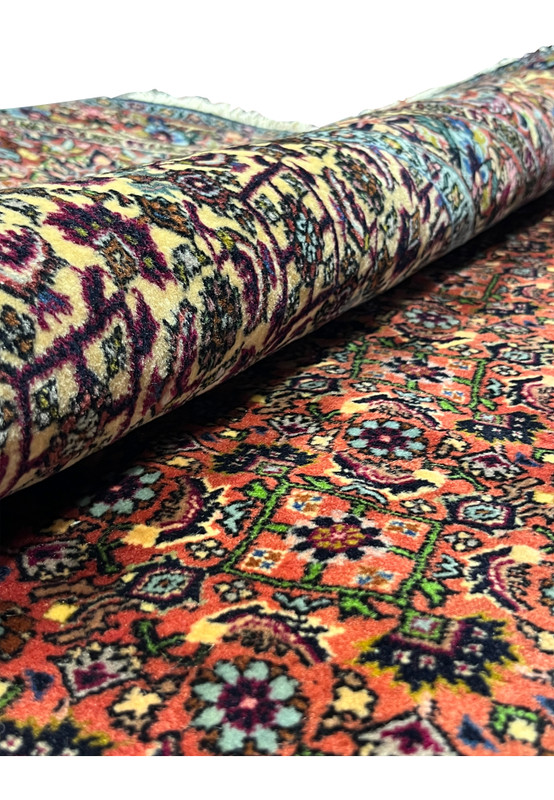 Rolled view of the Persian Bijar Iron Rug showing thick wool pile, ivory floral medallion, and dense field pattern.