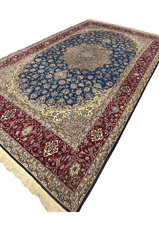 Angled perspective highlighting the shimmer of wool and silk across the blue field, medallion, and red borders.