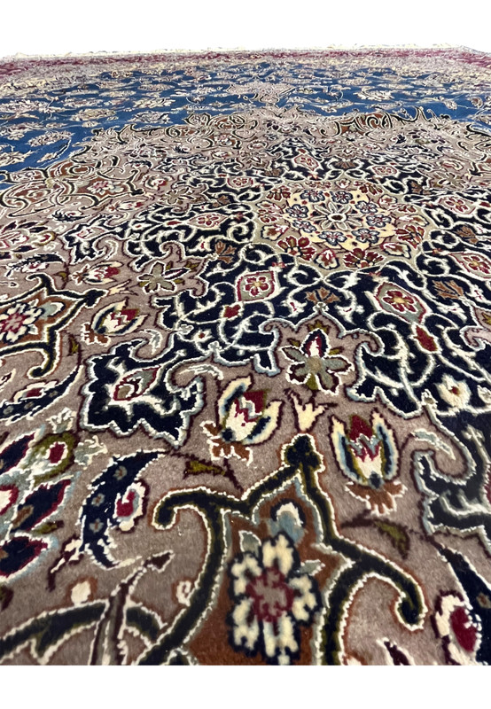 Low-angle detail view of the Persian Isfahan rug showing the floral motifs, navy and beige medallion work, and wool-silk texture across the field.