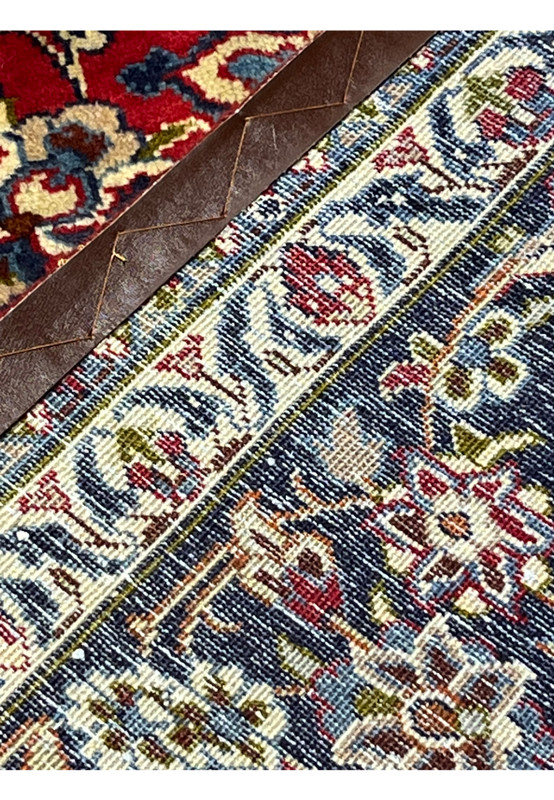 Backside close-up of 9'10 x 13'1 Persian Isfahan rug showing leather edging, fine knot structure, and detailed floral border pattern