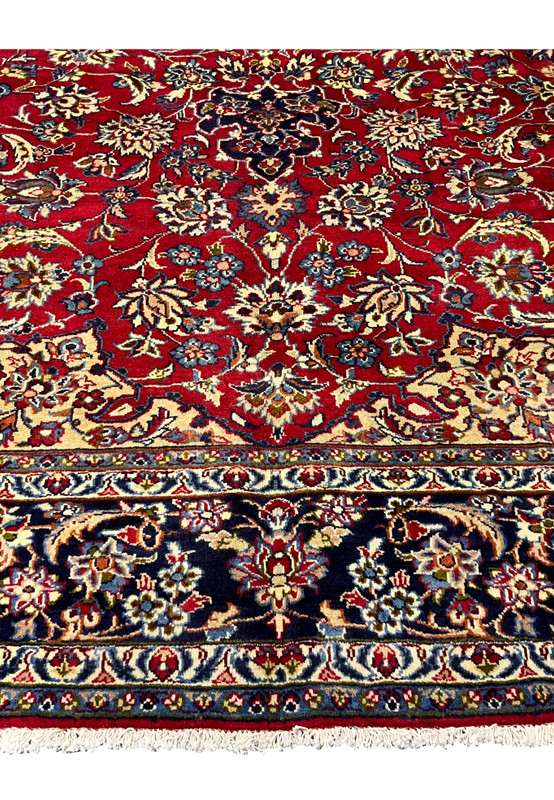 Close-up of Persian Isfahan rug border showing navy floral bands, vines, and small decorative motifs