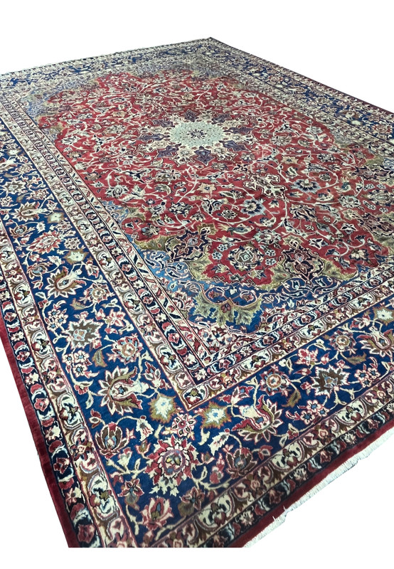 Angled view of the 9'9 x 14'5 Najafabad Persian rug highlighting the ruby field and strong navy border contrast.