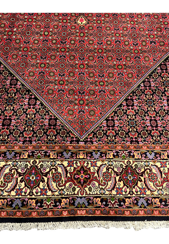 Lower border close-up of Persian Bijar rug showing thick wool pile, ivory floral scrollwork, navy outlines, and tightly packed construction