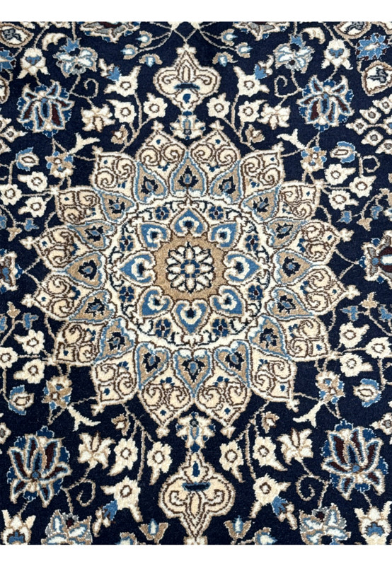 Close up of ivory and beige medallion on navy Persian Nain rug with sky blue petals and soft gold detailing