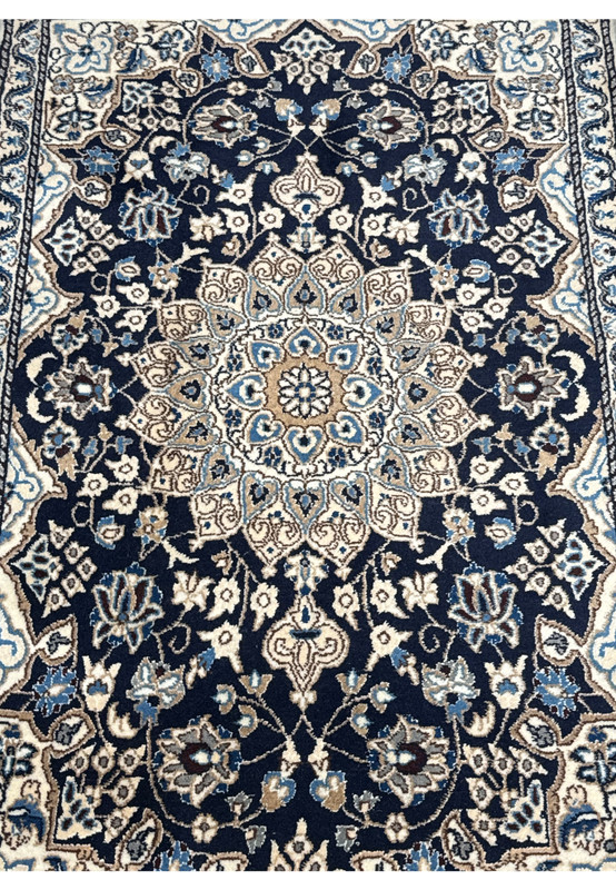 Midfield detail of Persian Nain rug with dark navy blue field, ivory floral vines, sky blue flowers, and soft gold accents
