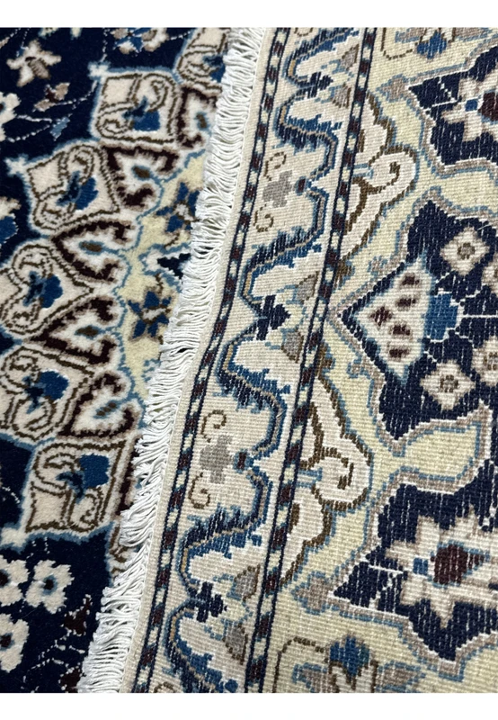 Backside of hand knotted Persian Nain rug showing cotton foundation and fine weave