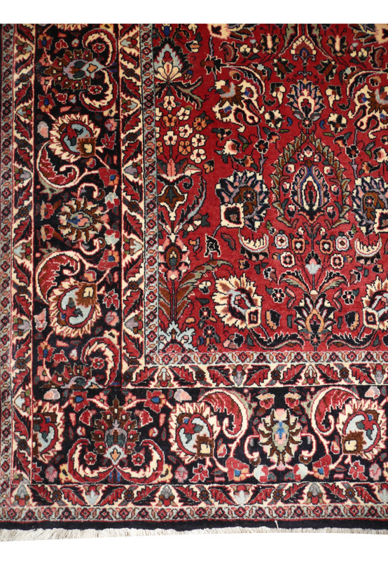 Close view of the all over floral midfield on a 6'6 x 9'6 Persian Bijar iron rug with brick red and navy tones