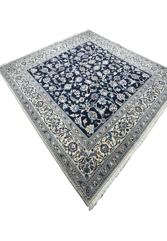Angled perspective of square Persian Nain rug highlighting fine wool pile, crisp floral pattern, and elegant border detail