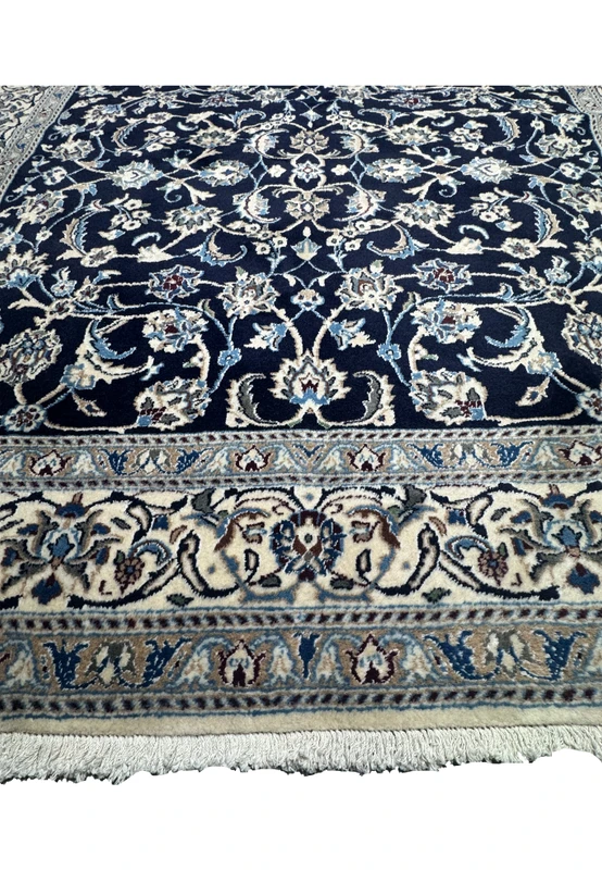 Lower border detail of Persian Nain rug featuring ivory floral cartouches with light blue and taupe color accents
