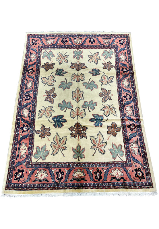 Top view of a Persian Farahan rug showing evenly spaced botanical leaf pattern on an ivory wool field