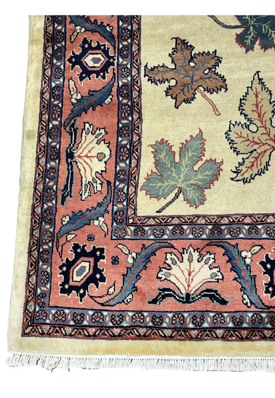 Border detail of a Persian Farahan rug with salmon pink ground, vine motifs, and navy floral accents