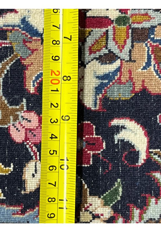Back of signed Persian Mashad Saber rug showing tight hand-knotted foundation with ruler measuring knot density