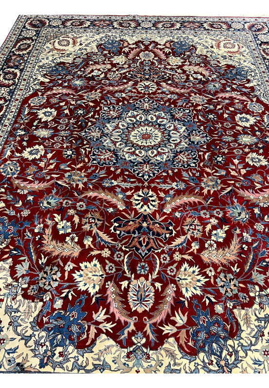 Top view of Persian Isfahan rug with symmetrical floral design, finely detailed medallion, and balanced red, ivory, and blue colors