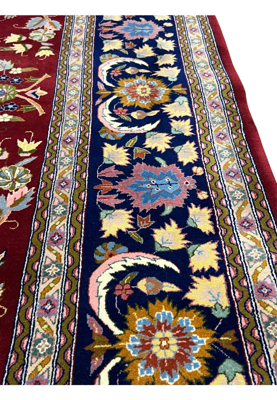Close-up of navy border on Persian Isfahan rug with floral rosettes, palmettes, and vine motifs