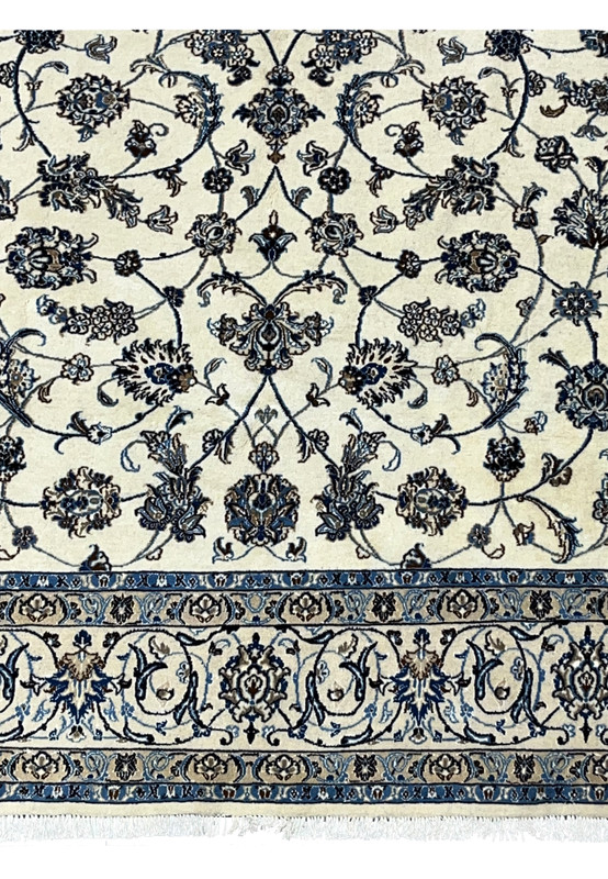 Lower border detail of Persian Nain rug with scrolling floral vines and blue accents