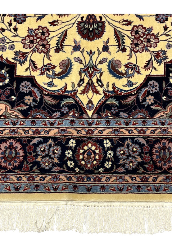 Lower border detail of Persian Tabriz rug with repeating floral rosettes on navy groun