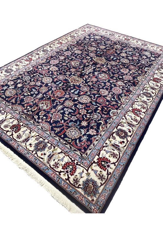 Angled view of a 5'7 x 8 navy blue Persian Sarough kork rug showing dense floral field, ivory border, and deep saturated wool pile