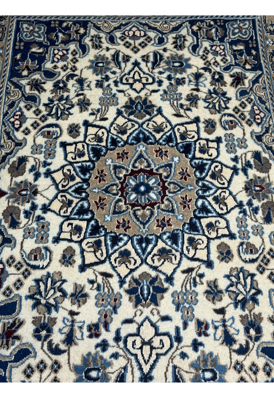 Close-up of blue medallion with floral motifs on ivory field in hand knotted Persian Nain rug