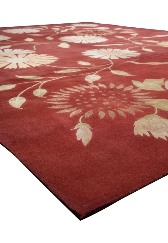 Angled perspective of a modern Tibetan wool and silk rug showing the rich red background, botanical floral design, and subtle silk sheen across the surface