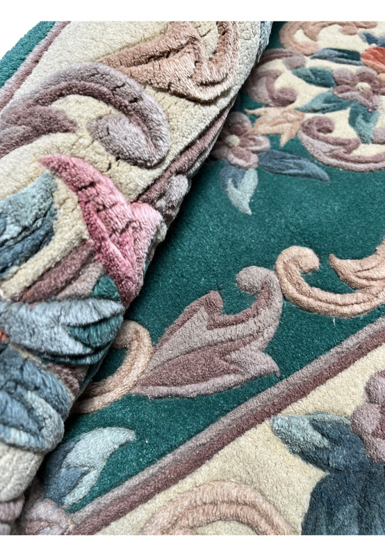 Rolled Aubusson Art Deco rug displaying thickness, plush texture, raised floral details, and tightly woven emerald green foundation