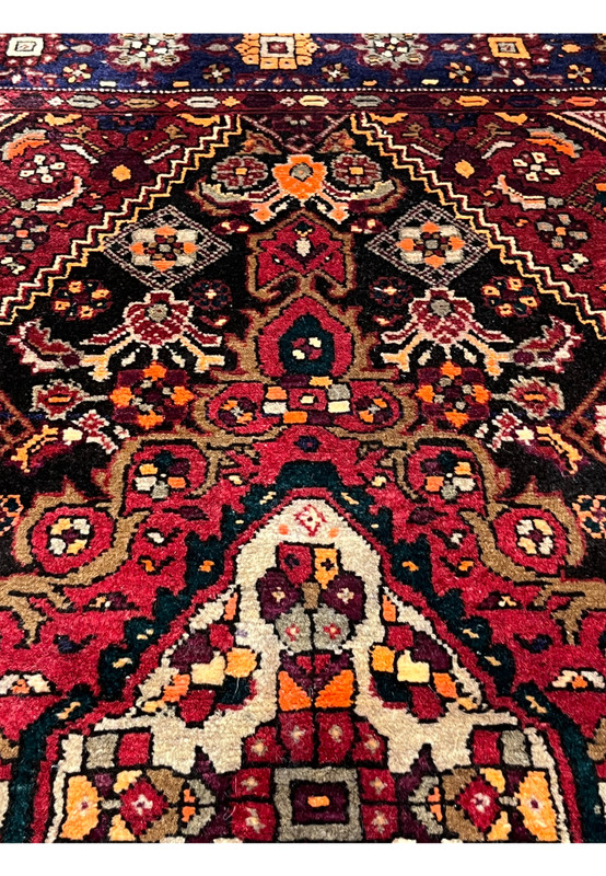 Upper field detail of a 3'4 x 5'5 Persian Gholtogh rug showing dense tribal motifs, deep red ground, navy accents, and crisp geometric symmetry