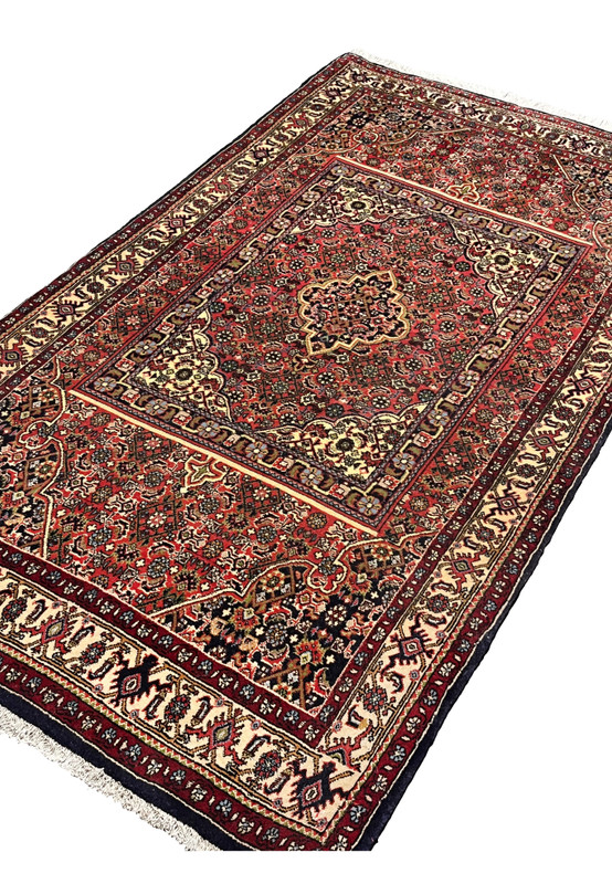 Angled perspective of a Persian Bijar rug emphasizing thick wool pile, compact structure, rug-in-rug layout, and durable construction