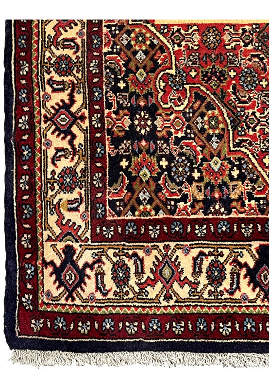 Border detail of a Persian Bijar rug showing repeating floral motifs, ivory ground, navy outlines, and precise hand-knotted craftsmanship