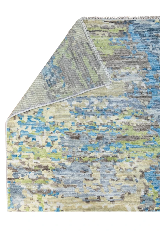 Folded corner detail of the modern Nepali abstract rug illustrating wool thickness, flexibility, and smooth edge binding with soft blue and ivory tones.