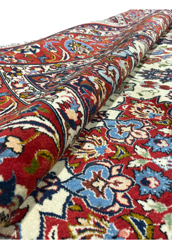 Rolled view of a Persian Isfahan rug illustrating flexibility, pile density, and smooth finish created by finely spun kork wool and silk
