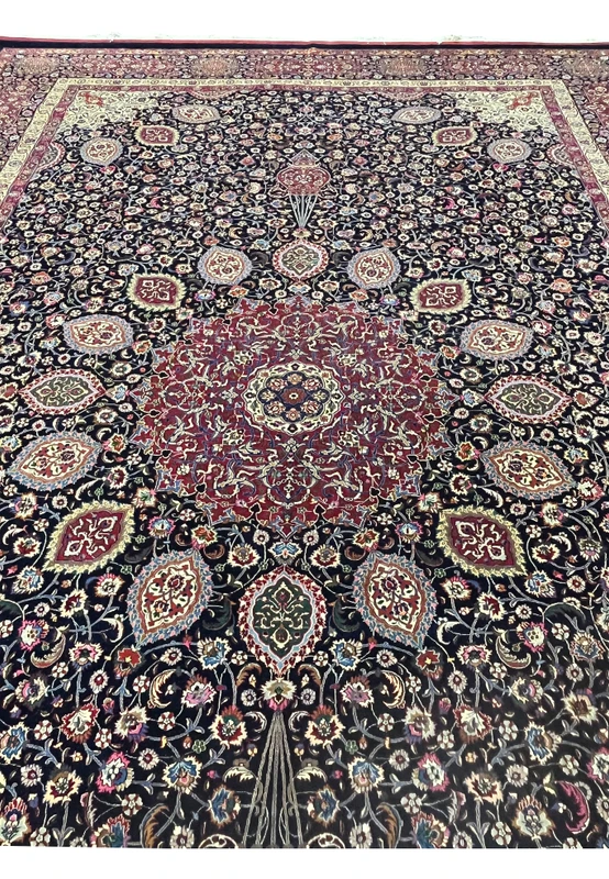 Midfield detail of Persian Mashad rug revealing dense floral patterning, scrolling vines, silk highlights, and deep navy background with balanced symmetry.