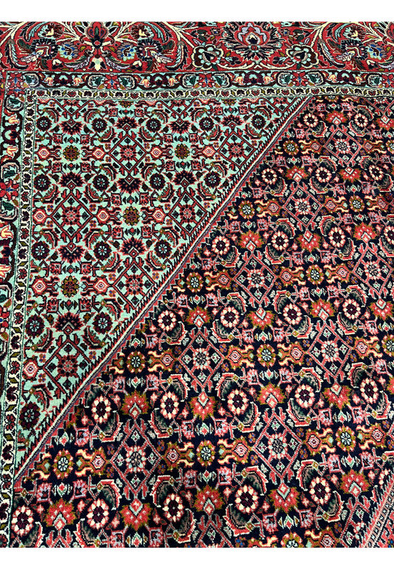 Color detail closeup of a Persian Bijar rug showing deep red, navy blue, ivory, olive green, and subtle light blue tones woven into dense wool