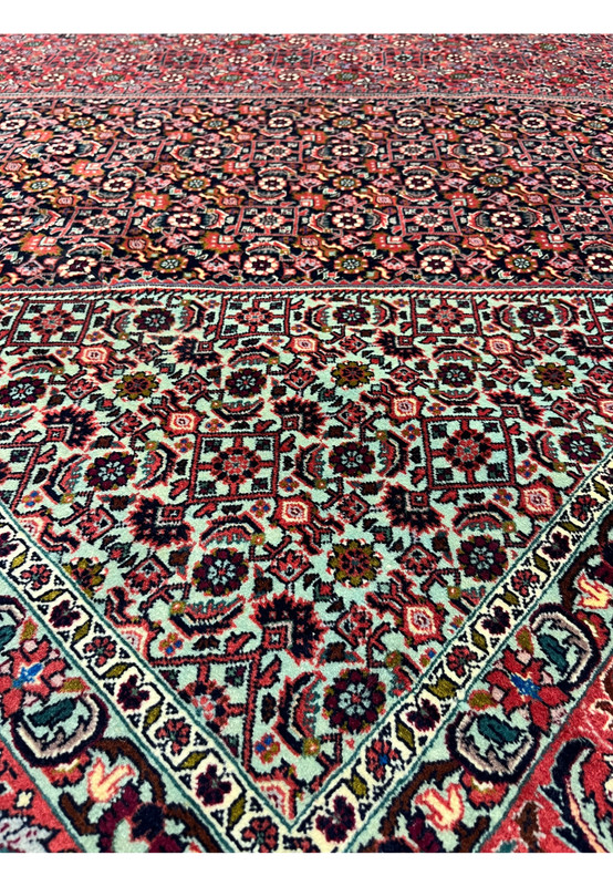 Inner border closeup of a Persian Bijar rug highlighting repeating geometric motifs, ivory background, red accents, and precise high-density wool weaving
