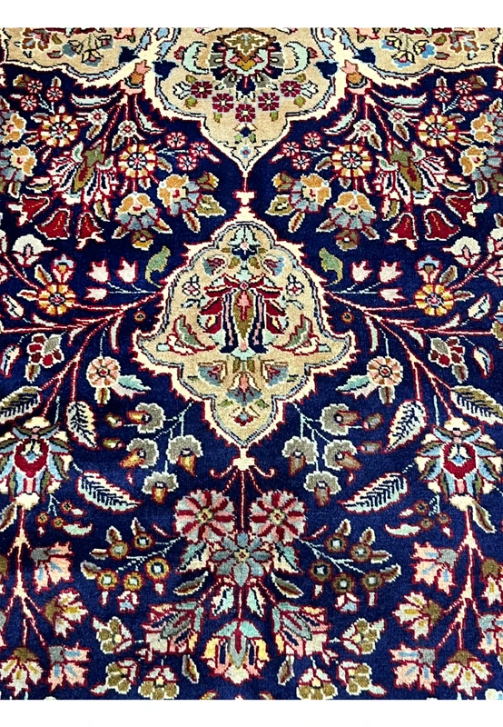 Floral motif close up on Persian Tabriz rug showing navy blue background, ivory outlines, burgundy flowers, and precise craftsmanship