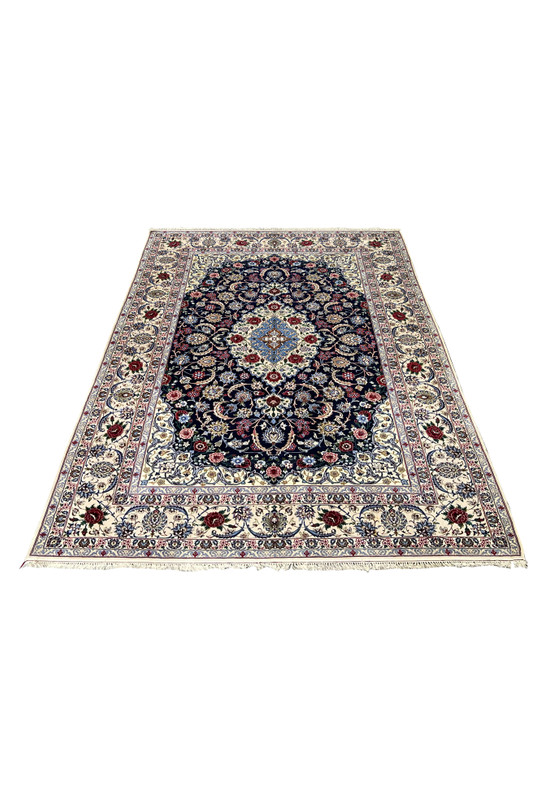 Laid down view of a 7 x 10 Persian Isfahan wool and silk rug showing balanced floral composition, navy background, ivory borders, and refined symmetry