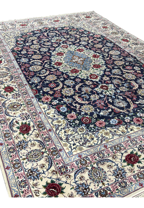 Angled view of a Persian Isfahan rug highlighting the navy field, elegant floral pattern, ivory borders, and refined wool and silk craftsmanship