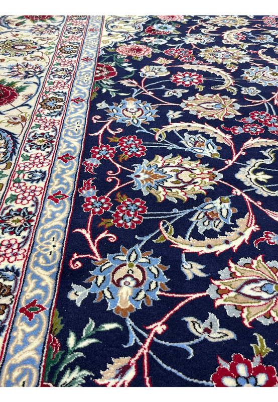 Detailed view of Persian Isfahan rug motifs featuring flowing floral patterns in navy blue, ivory, burgundy, light blue, and soft gold