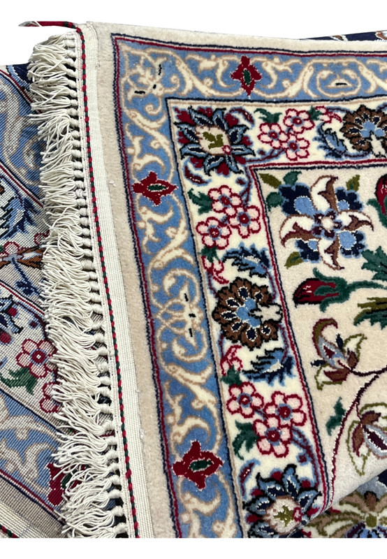 Folded corner of a 7x10 Persian Isfahan rug highlighting ivory border, floral detailing, crisp edges, and fine hand knotted construction
