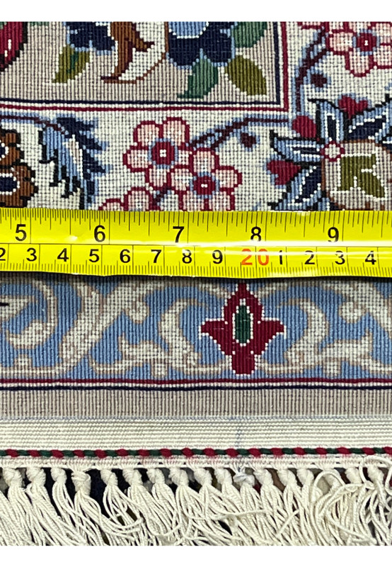 Close up of the backside of a Persian Isfahan rug with ruler showing fine knot density, detailed weave, and silk and wool foundation
