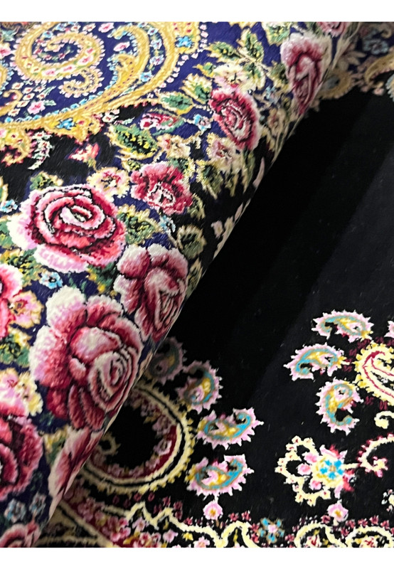 Rolled view of a signed Persian Qum silk rug showing thin profile, silk luster, and flexible hand-knotted structure