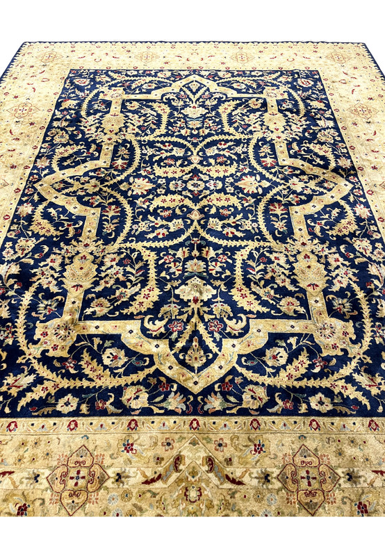 Midfield detail of a distressed Oriental Agra rug highlighting scrolling floral vines, faded navy background, softened gold accents, and natural color wear