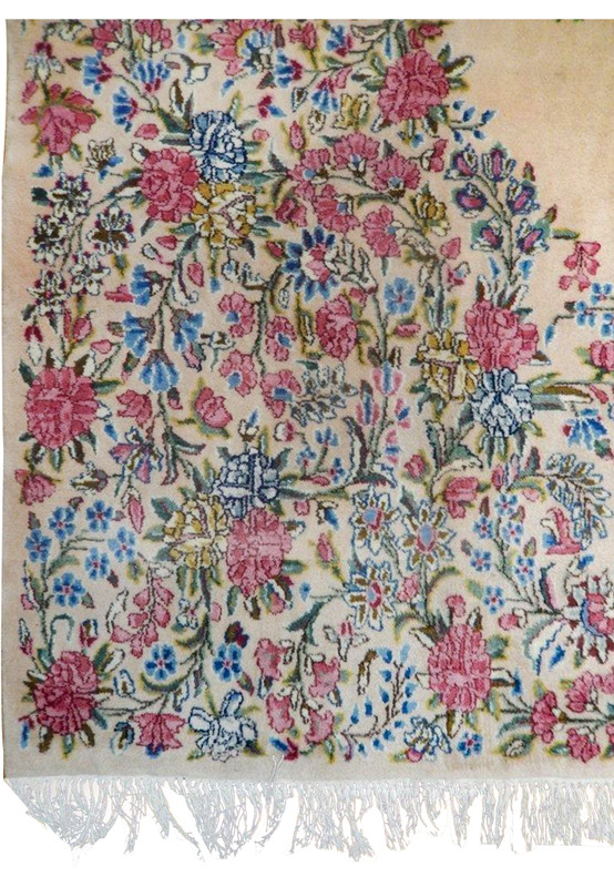 Detailed border view of a Persian Kerman rug with dense floral vines, pink roses, blue flowers, sage green leaves, and fine hand-knotted wool