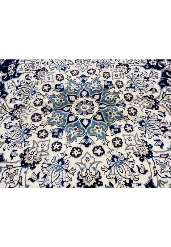 Inner medallion detail of a Persian Nain 9 La rug featuring ivory floral geometry, light blue highlights, and refined knot definition