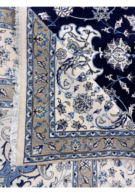 Rolled edge detail of a 10x19 Persian Nain 9 La rug showing fine knotting, navy blue field, ivory floral motifs, and precision hand finishing.