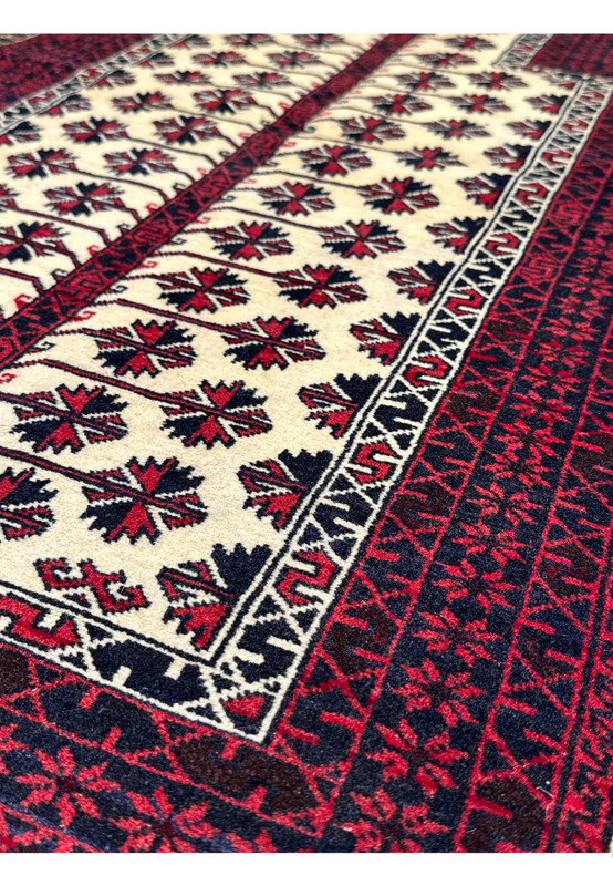 Angled perspective of a Persian Baluch prayer rug emphasizing wool pile texture, bold contrast, and geometric tribal design