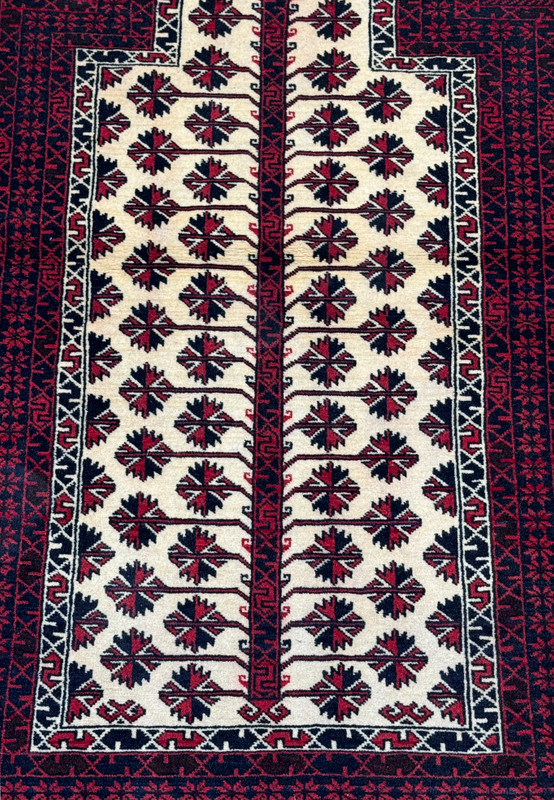 Midfield detail of a Khal Mohammadi style Persian Baluch prayer rug highlighting repeated floral motifs within the ivory prayer niche
