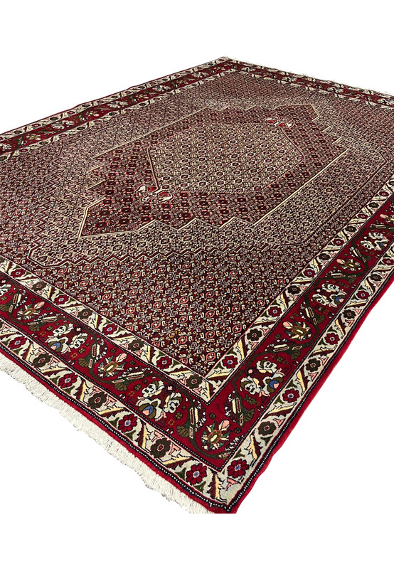 Angled view of Persian Senneh rug revealing surface texture, dense knotting, stepped medallion depth, and color contrast